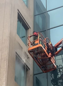 Nettoyage sécuritaire d’une façade vitrée en hauteur à l’aide d’un élévateur.