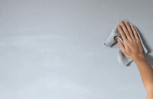 Personne nettoyant un mur avec un chiffon doux pour éviter d’endommager la surface.