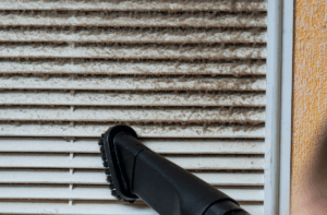 Nettoyage des grilles de ventilation avec un aspirateur équipé d'un filtre HEPA pour éliminer la poussière.